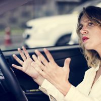 Women making gestures in her car about preventing road rage