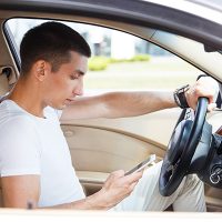 Image of a young man using his cell phone while driving