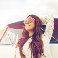 picture of a woman smiling next to a car in the sunshine