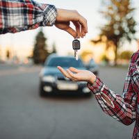 Image of a driving instructor giving the keys to a student who is taking her driving test