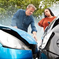 Two drivers who were involved in a car accident surveying the damage