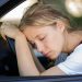 Image of a woman who has fallen asleep at the wheel, demonstrating the danger of driving while drowsy.
